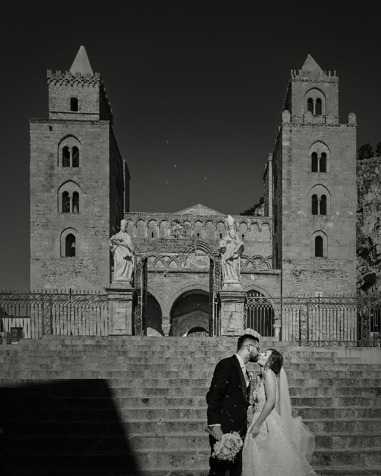 Dramatic black and white sequence of a couple in front of a gothic stone church with twin towers.