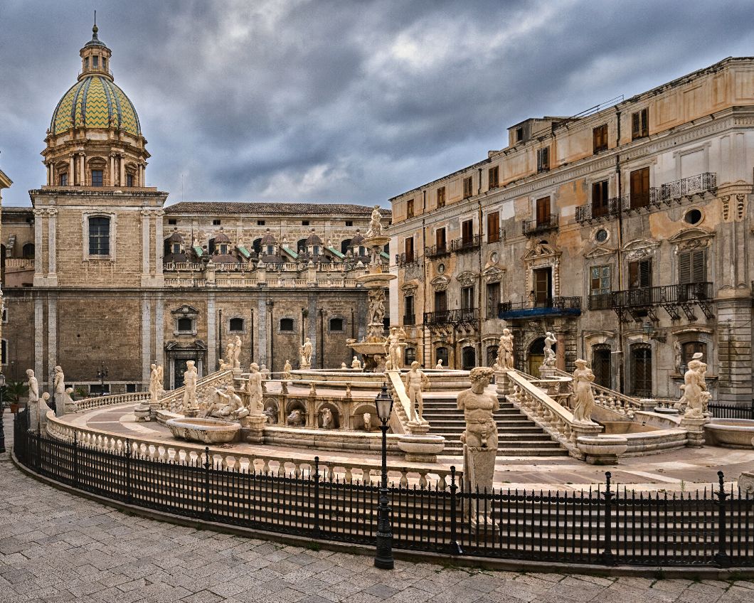 Panoramic view of historic Baroque architecture in Noto, Sicily with ornate buildings and balustrades under dramatic clouds.