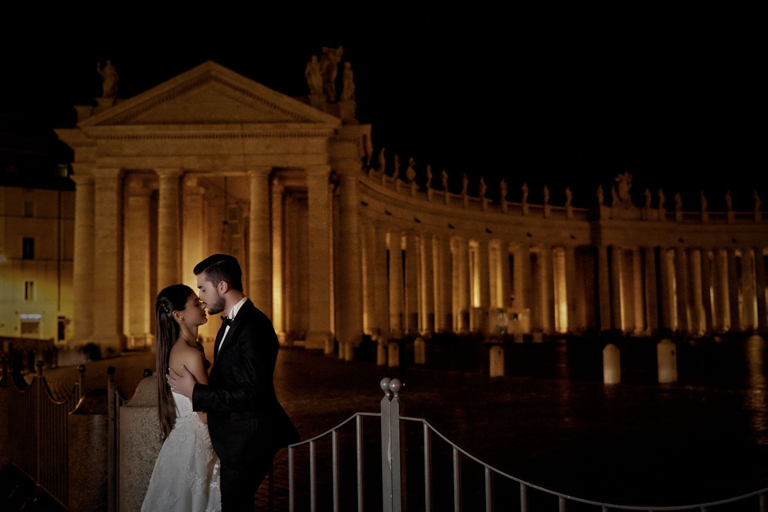 Illuminated classical architecture at night with columns and arches.