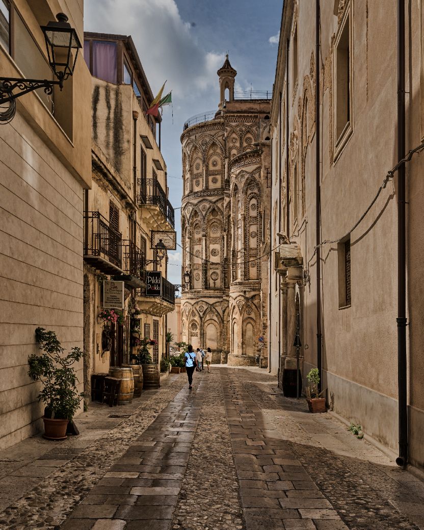 Narrow cobblestone street in historic Italian town with ornate cathedral facade visible at the end of the alley.
Horvath-Photography