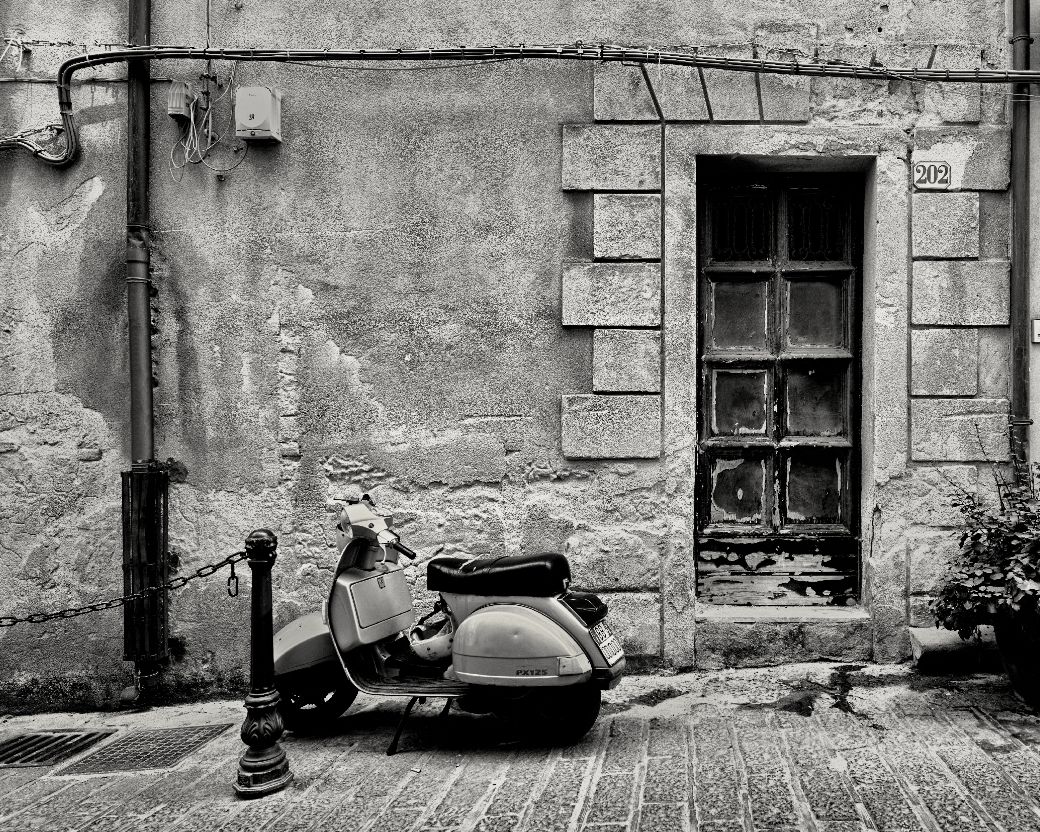 A series of five black and white architectural photographs showing old stone building facades with windows and doorways.