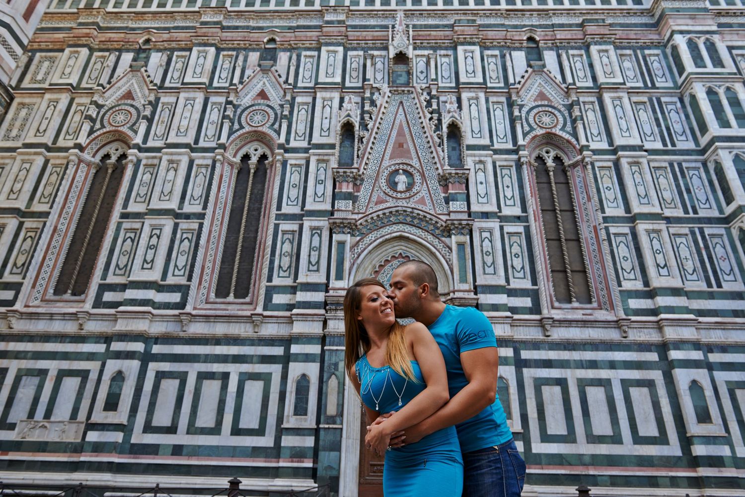 A couple in blue outfits shares a romantic moment in front of the ornate facade of Florence's Duomo cathedral.
Horvath-Photography