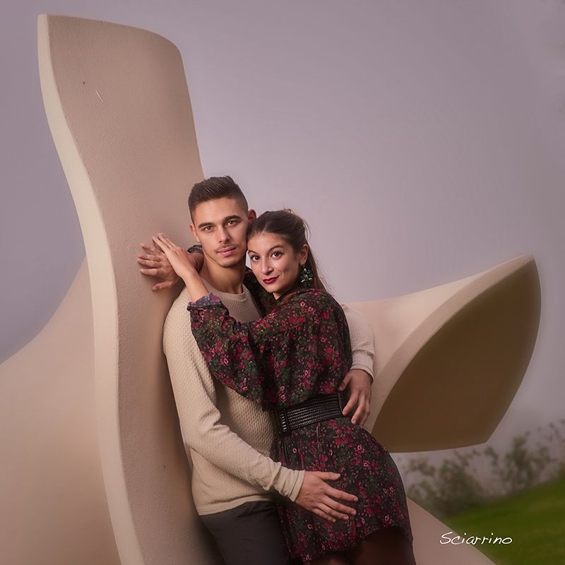 A romantic couple poses together against a neutral backdrop in a professional studio photoshoot.