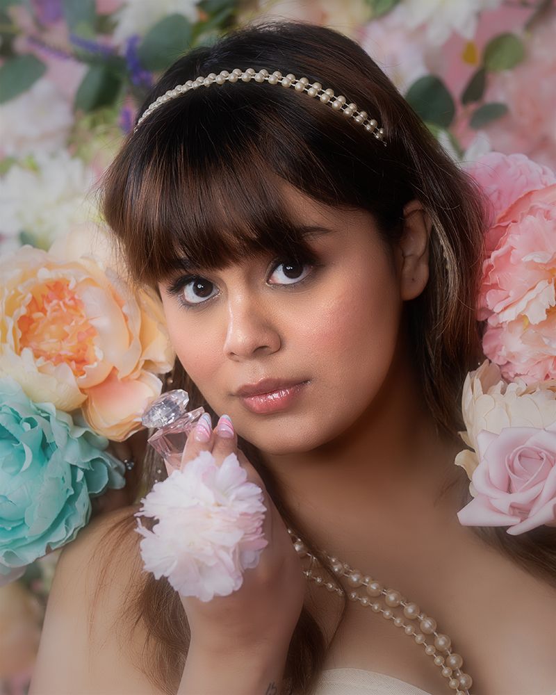 Artistic portrait with soft floral backdrop featuring delicate pearls and romantic pastel blooms.