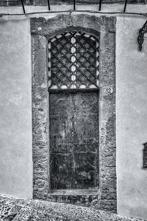A black and white photograph shows a series of arched windows and columns along an old stone building's exterior wall.
Horvath-Photography-