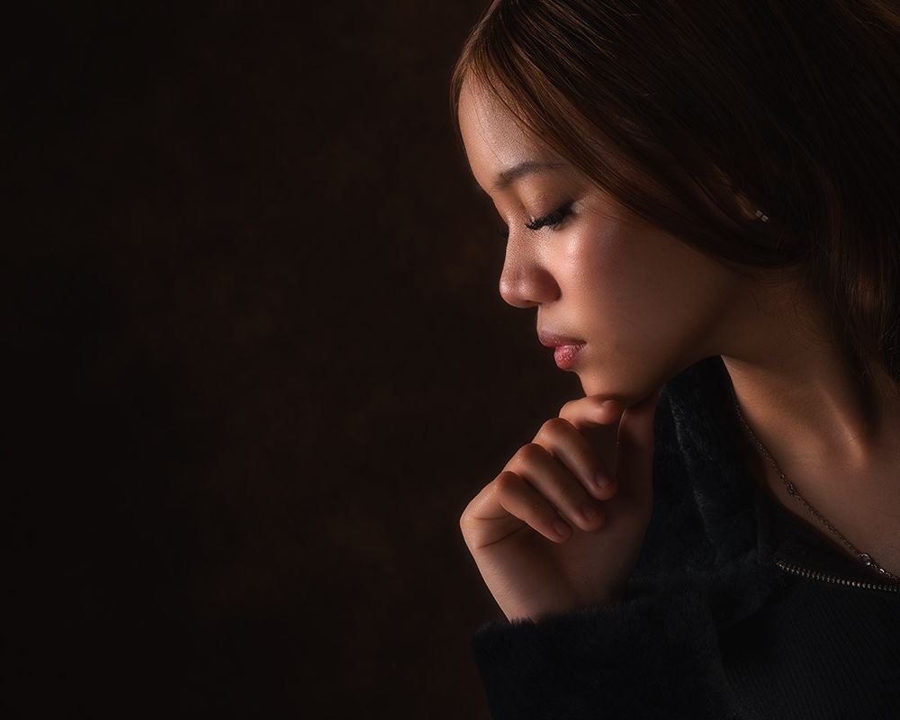 A dramatic side profile portrait in low key lighting against a dark background.