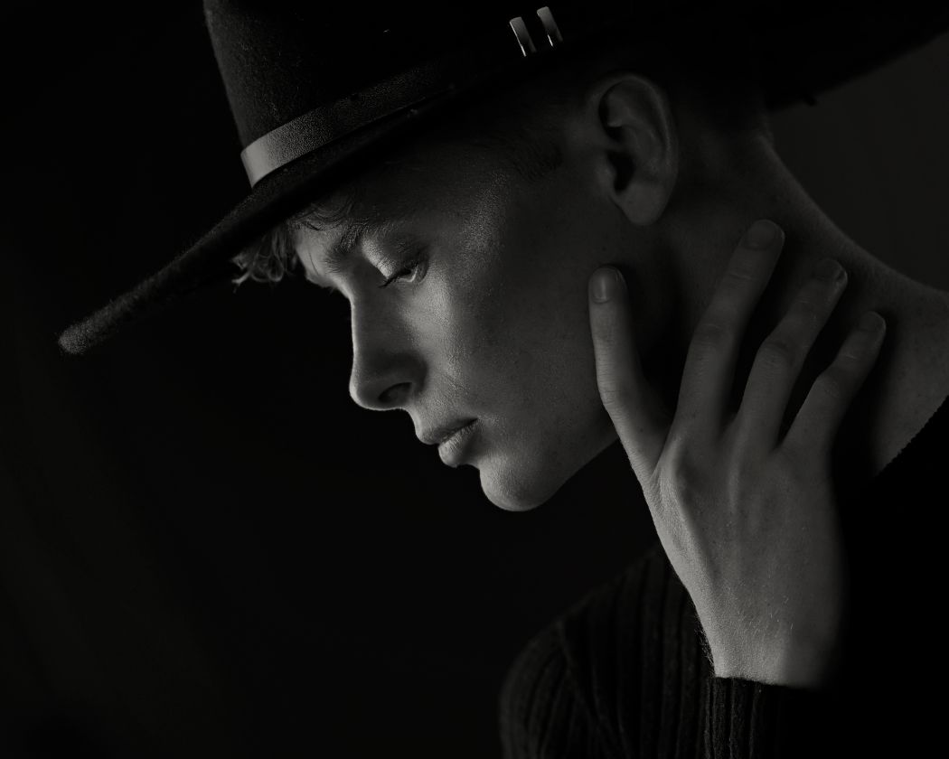 A series of black and white profile portraits in dramatic low-key lighting showing contemplative poses and shadows.