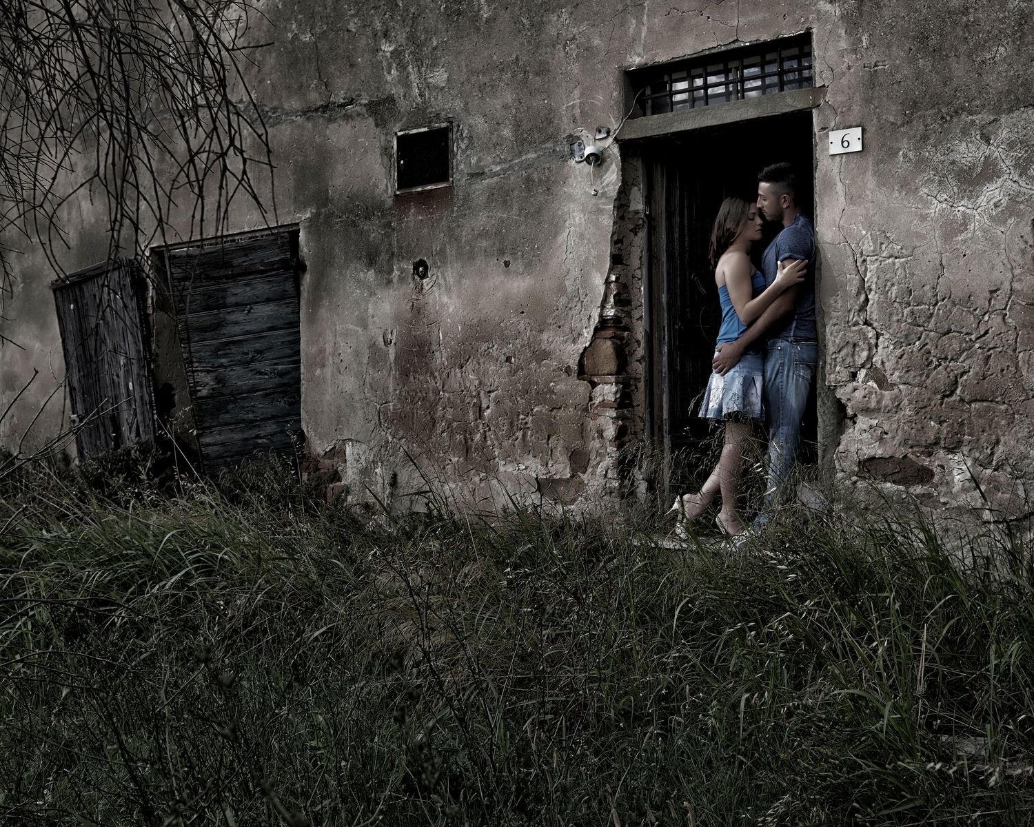 A series of dark doorways in a weathered concrete wall with grass growing at the base.
Horvath-Photography-Sam-Sciarrino