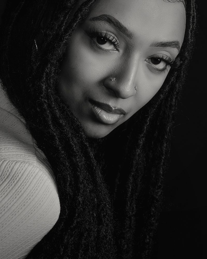 Artistic black and white portraits featuring dreadlocks and gentle expressions in moody lighting.