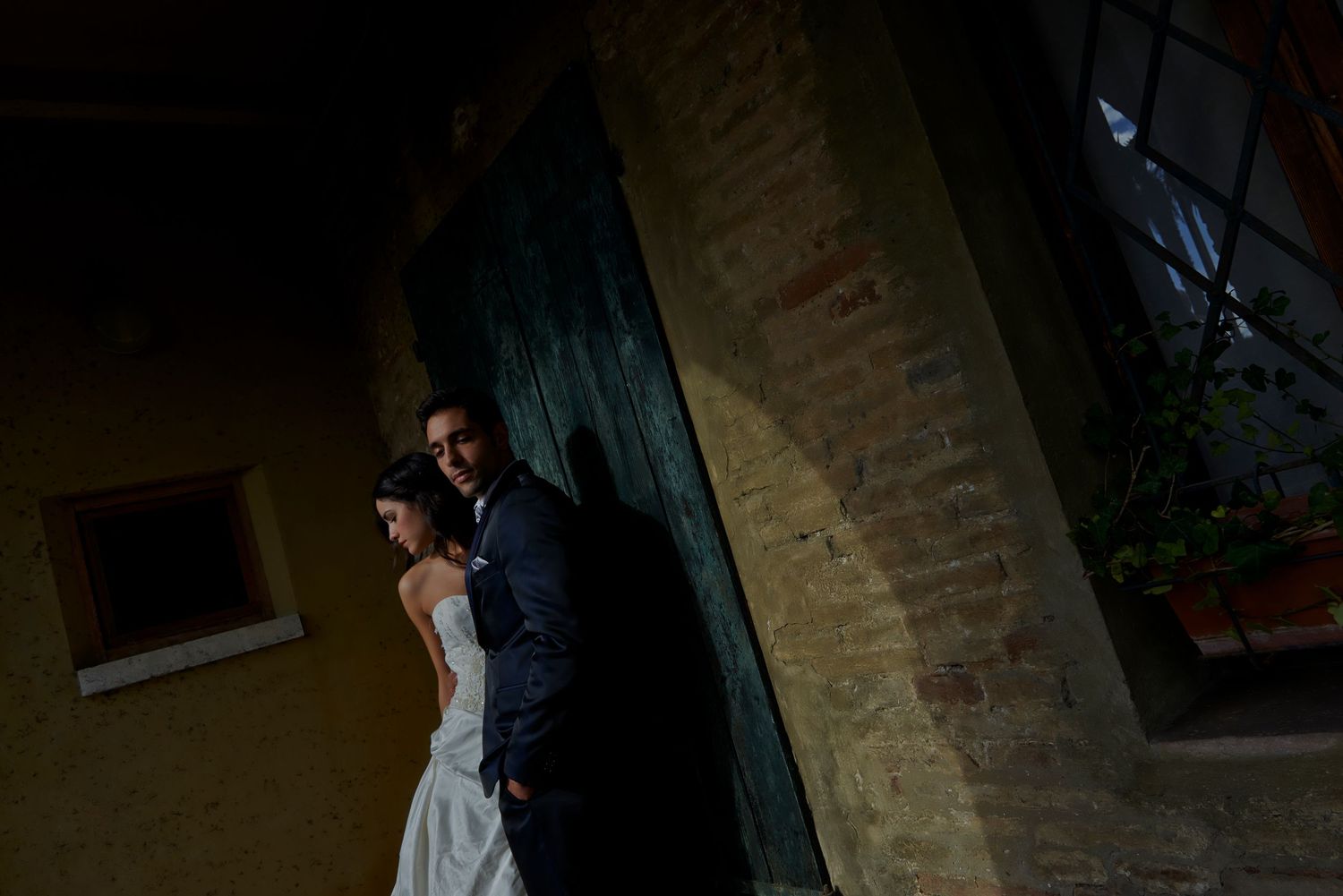 A couple in wedding attire poses together against a rustic stone wall in dramatic low-light photography.
Horvath-Photography-Sam-Sciarrino