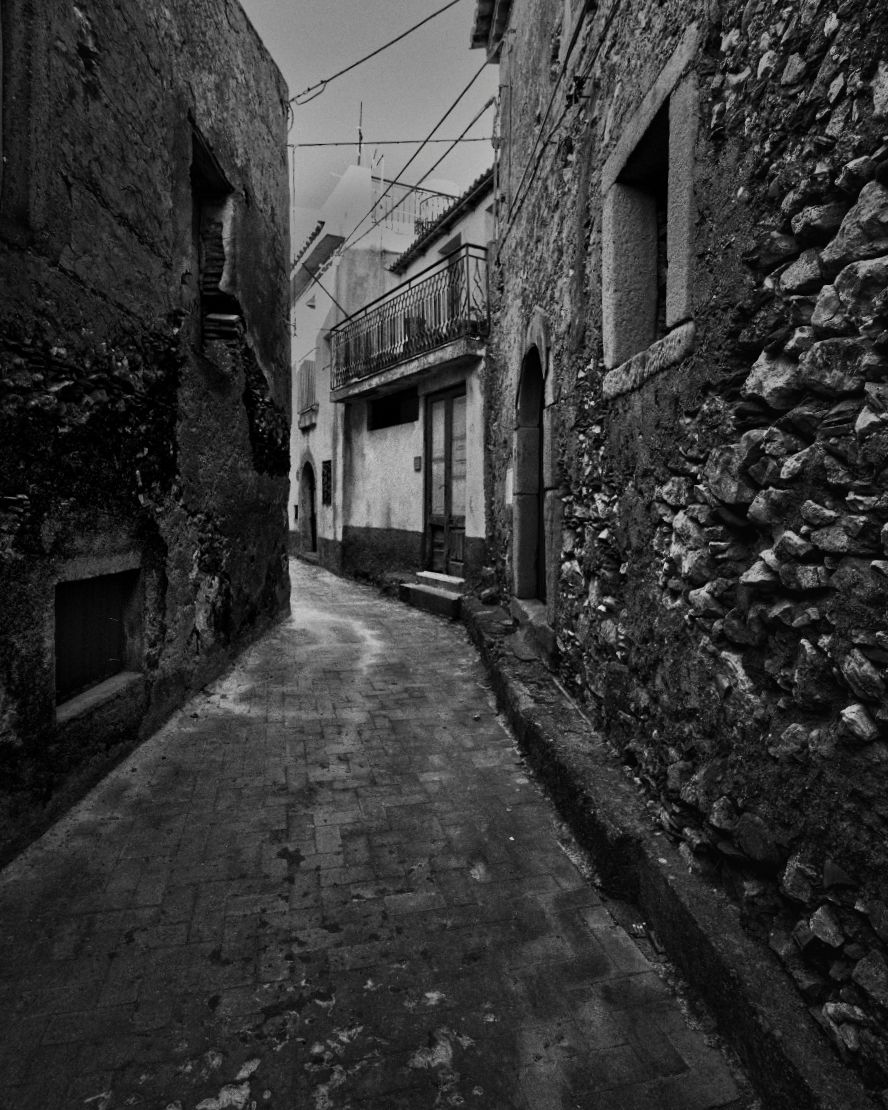 Narrow cobblestone alleyways with stone walls and rustic architecture captured in dramatic black and white photography.
Horvath-Photography-