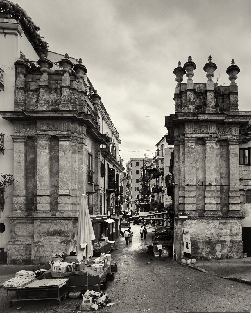 Panoramic series of vintage black and white photographs showing stone pillars and architectural details of a city street.