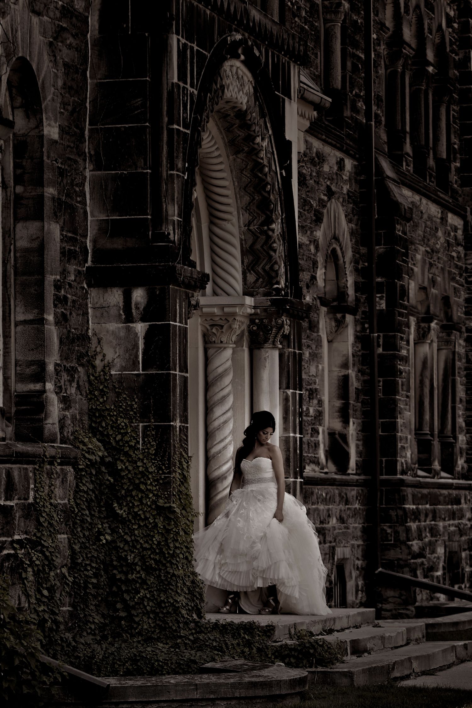 A person in a white wedding dress stands at the entrance of a Gothic stone church with ornate architectural details.
Horvath-Photography