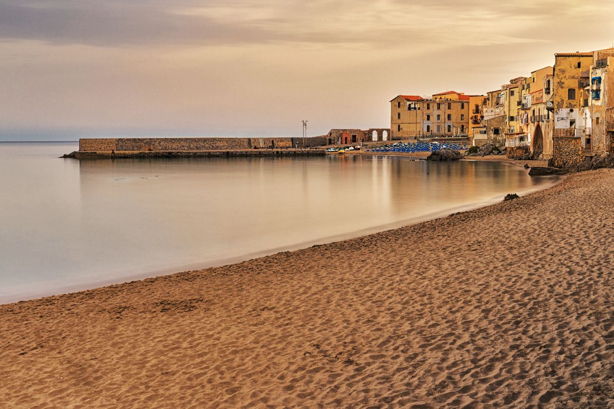 Cefalu Sicily  sunset view of colorful buildings along a sandy Mediterranean beach with calm waters.
Horvath-Photography-Sam-Sciarrino