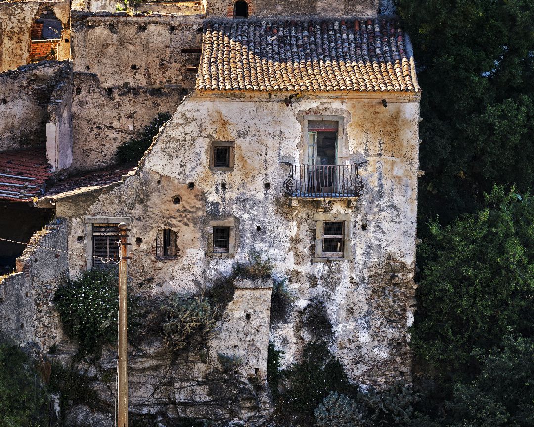 Ancient stone ruins with crumbling walls and tiled roofs stand against a backdrop of green foliage.
Horvath-Photography-Sam-Sciarrino