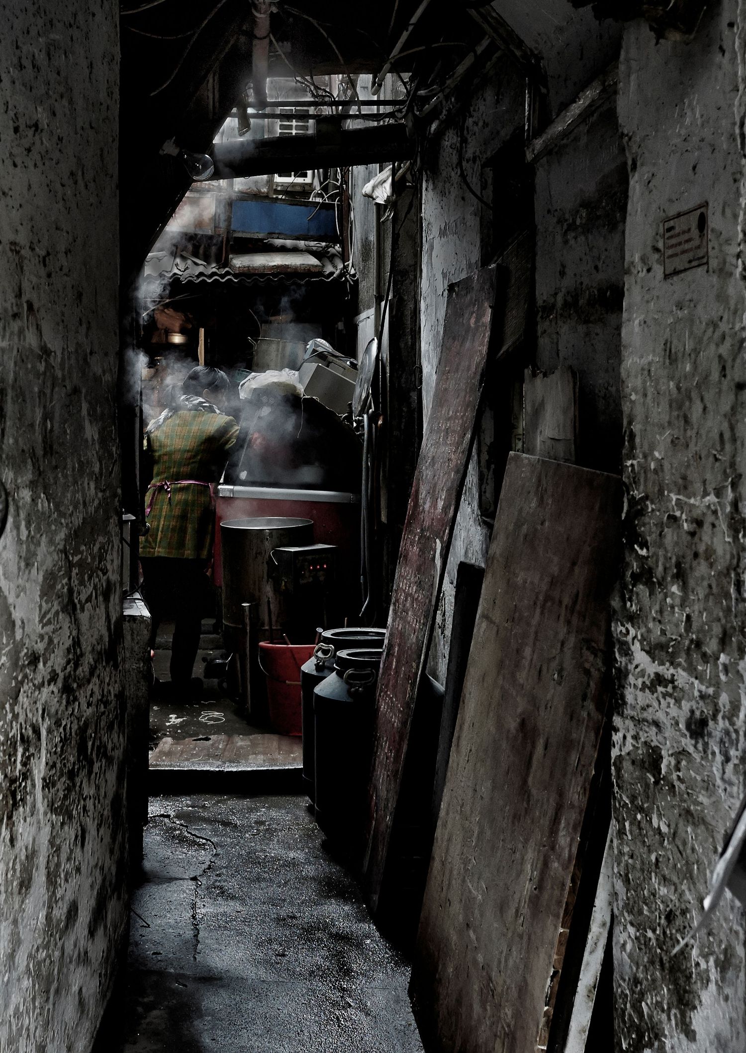Dark urban alleyway with stone pillars and walls creating a moody atmospheric corridor in low light conditions.