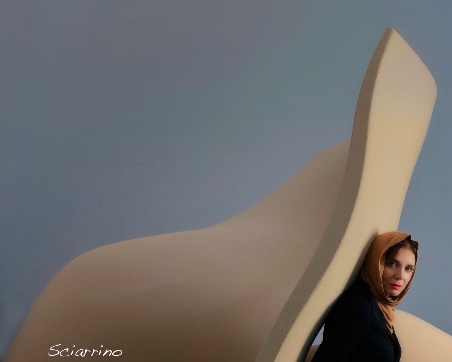 Minimalist fashion photo series featuring a model posing with a curved white architectural element against blue backdrop.