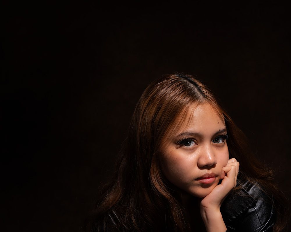 Dramatic portrait series in dark moody lighting with black background and contemplative expressions.