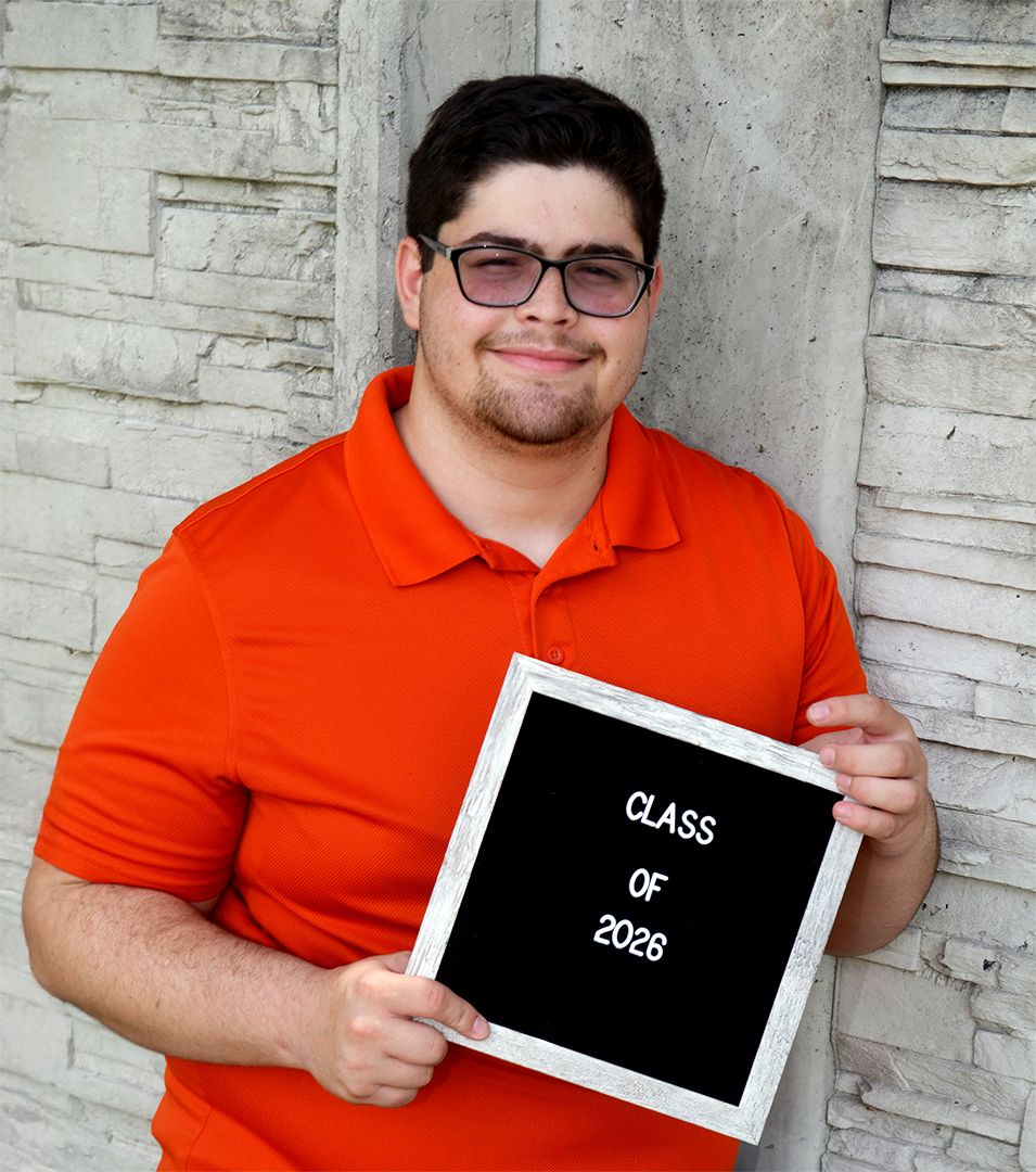 High school senior holding Class of 2026 sign during graduation photography session in Brevard County, Florida