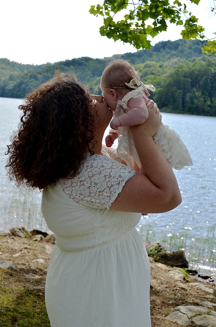 Mother lifting daughter and kissing her cheek during family portrait session