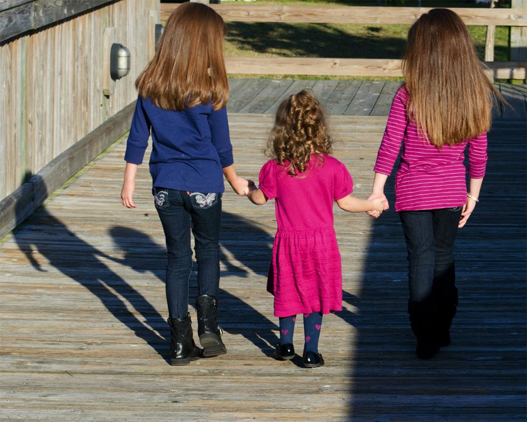 Three siblings walking on a bridge during family photography session in Brevard County, Florida