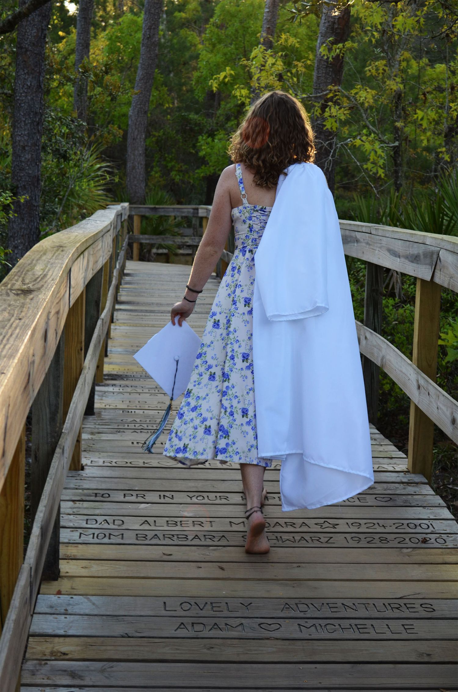 High school senior walking outdoors holding cap and gown during graduation portrait session in Brevard County, Florida