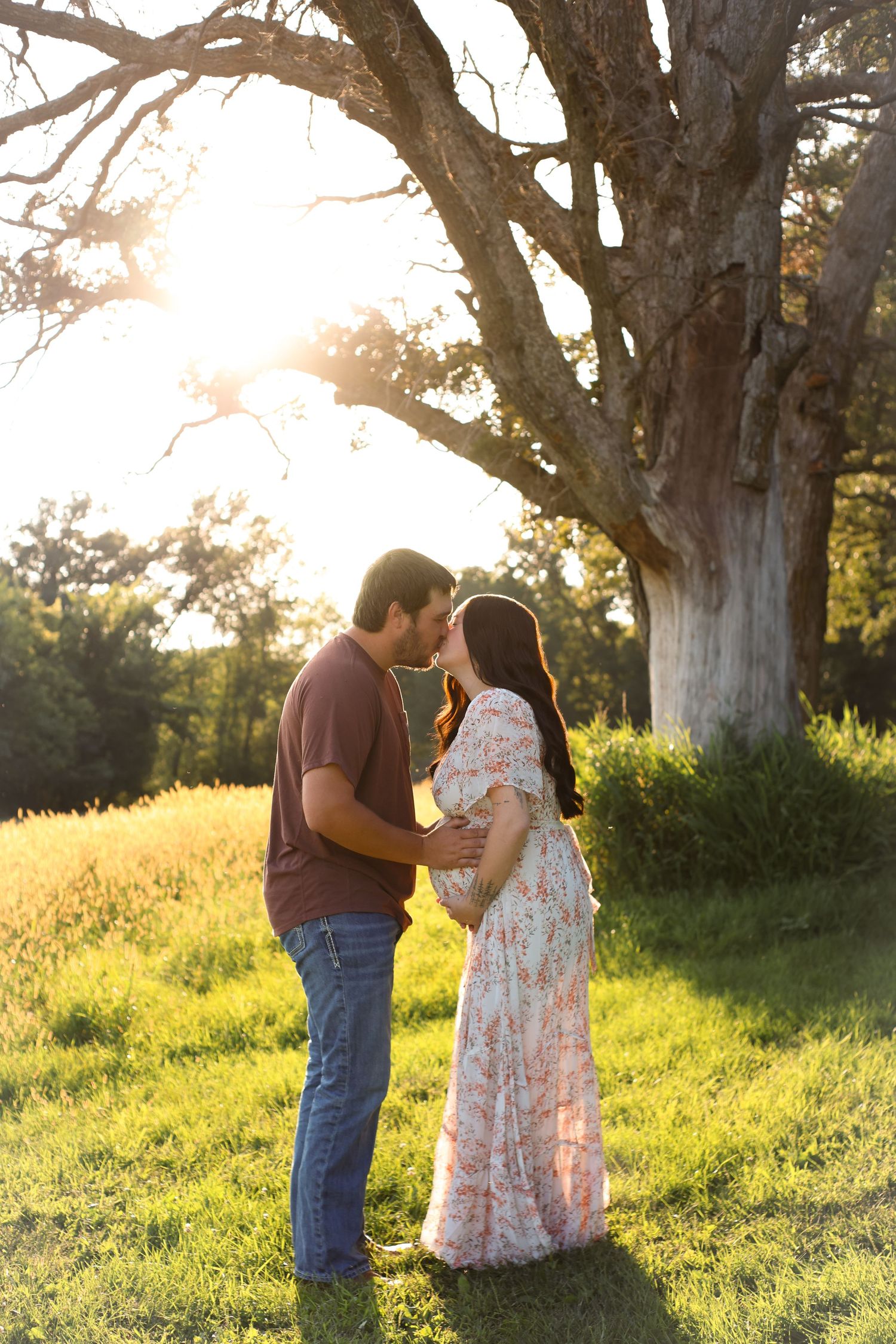 Romantic moment between couple in field with flowering trees at golden hour.