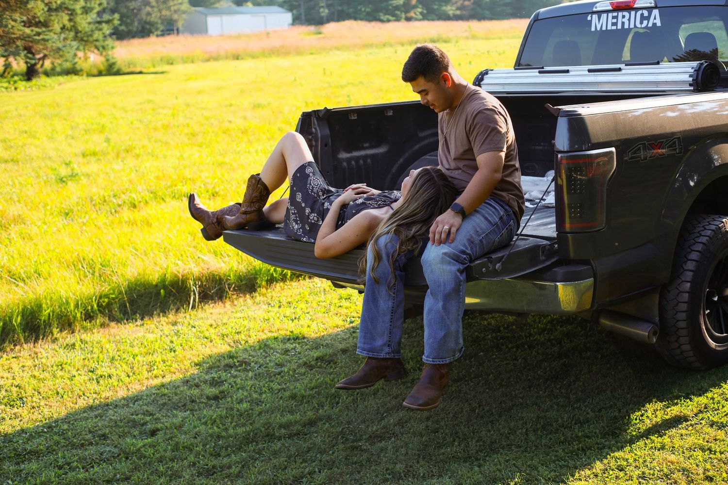 People relaxing on the tailgate of a pickup truck in a sunny yellow field.