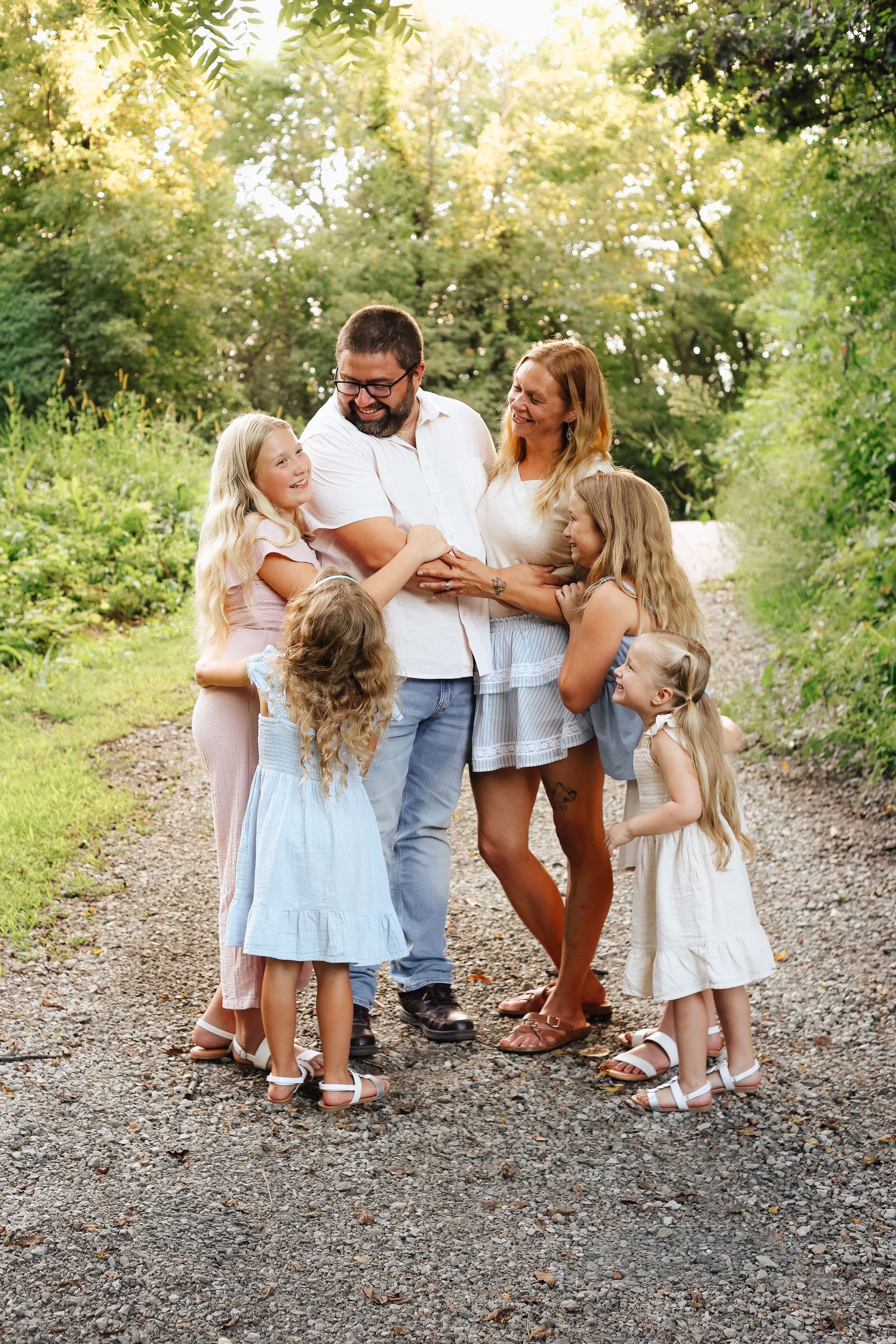 Family members share hugs and laughter during an outdoor photo session.