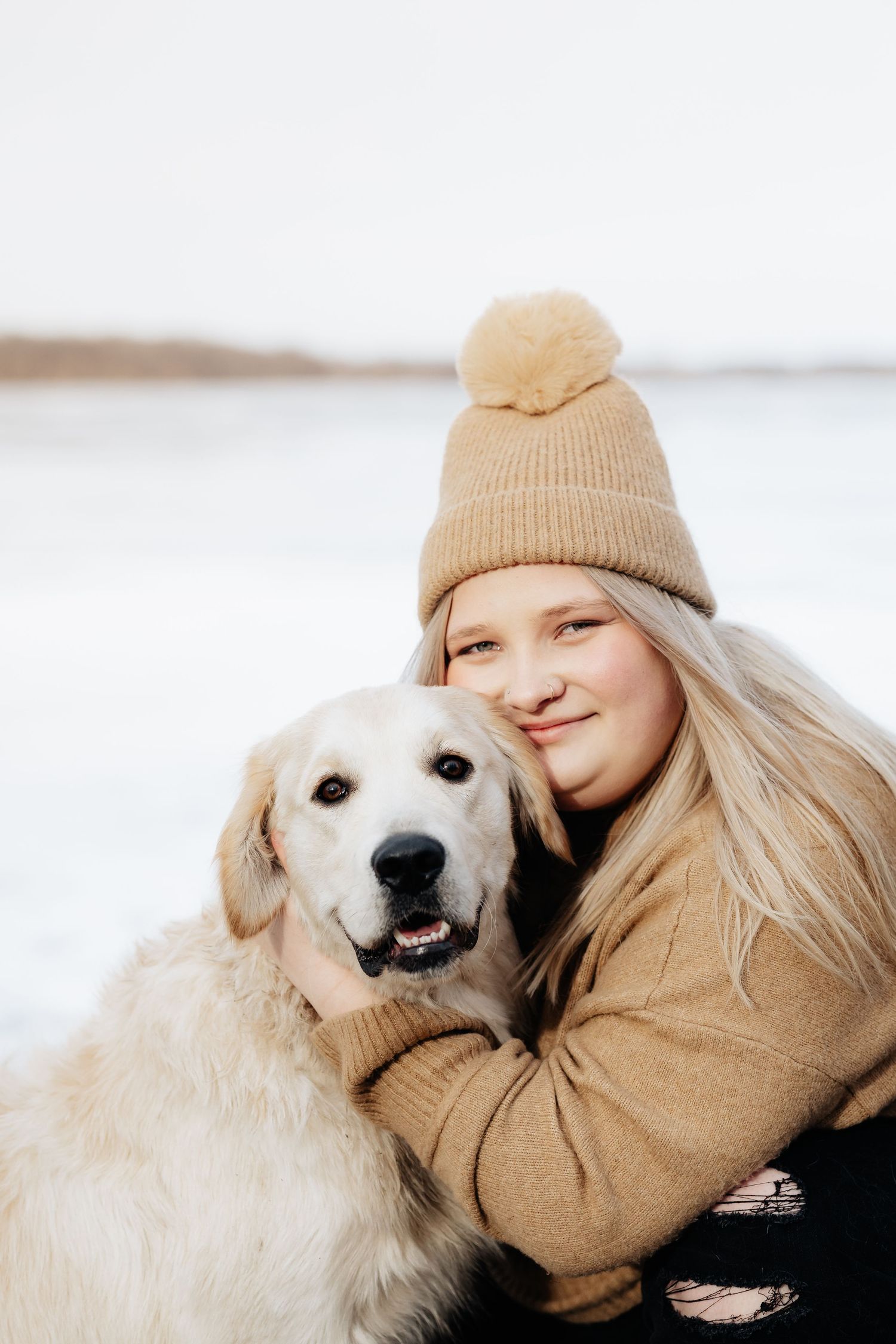 Golden retriever and person wearing beige knit hat share a heartwarming moment outdoors in winter.