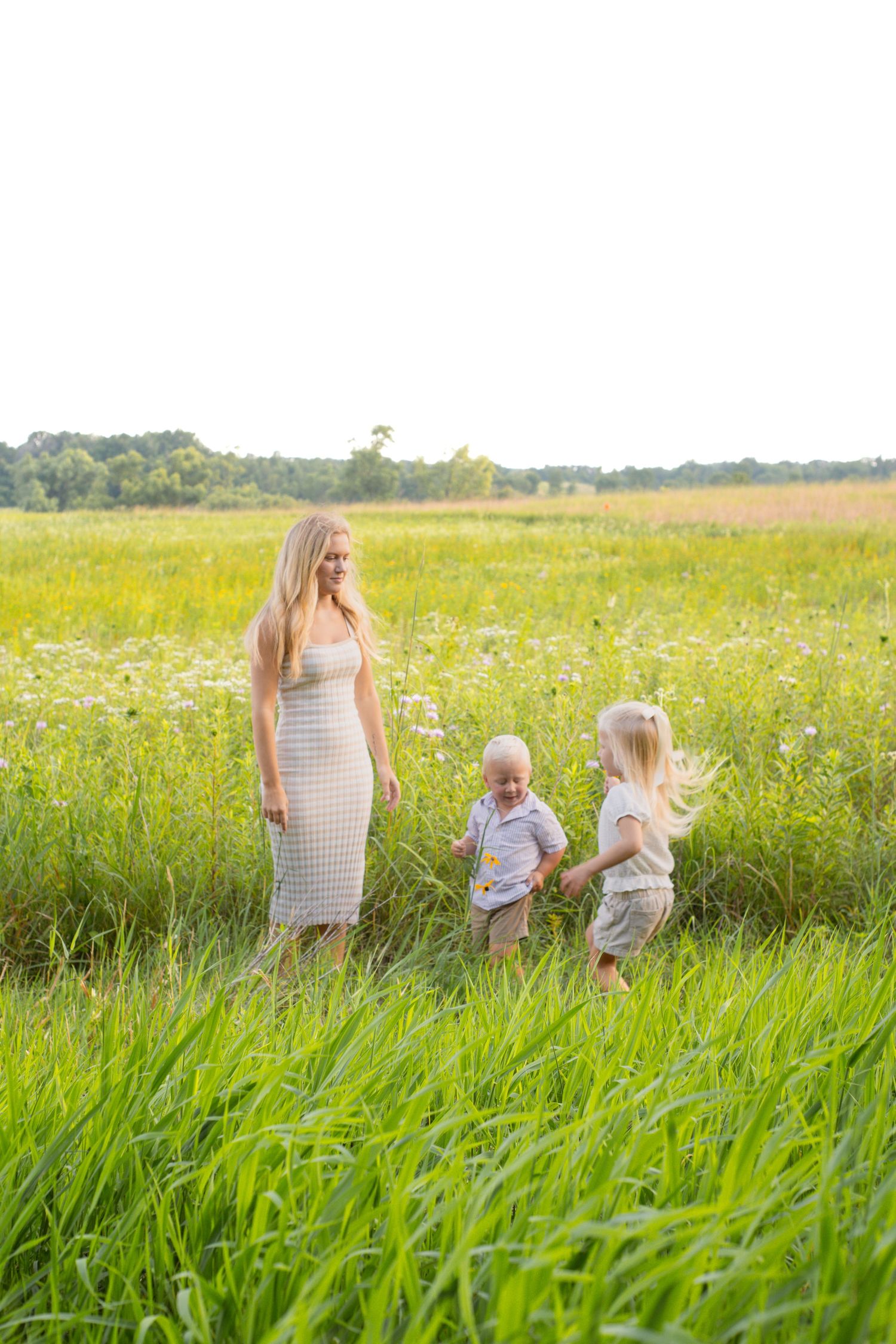 A family walking through tall grass in a sunny meadow.