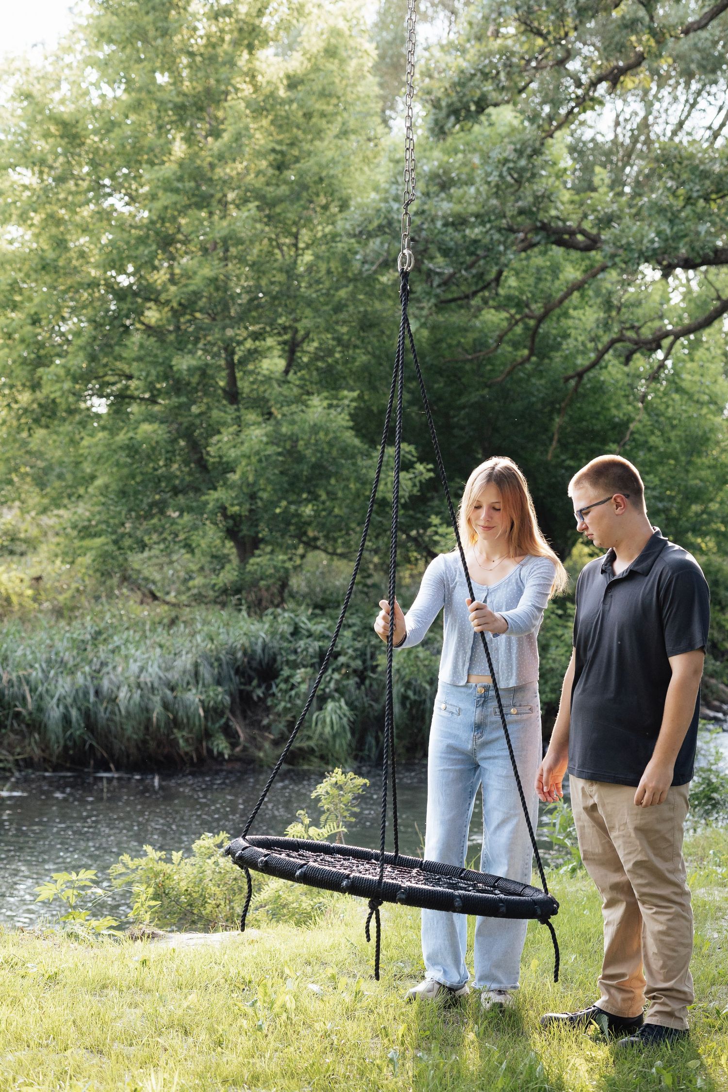 People setting up fishing equipment by a pond on a sunny day.