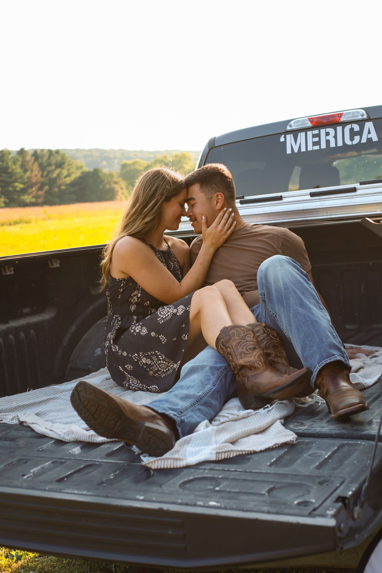 Couple sharing intimate moment in pickup truck bed at sunset.