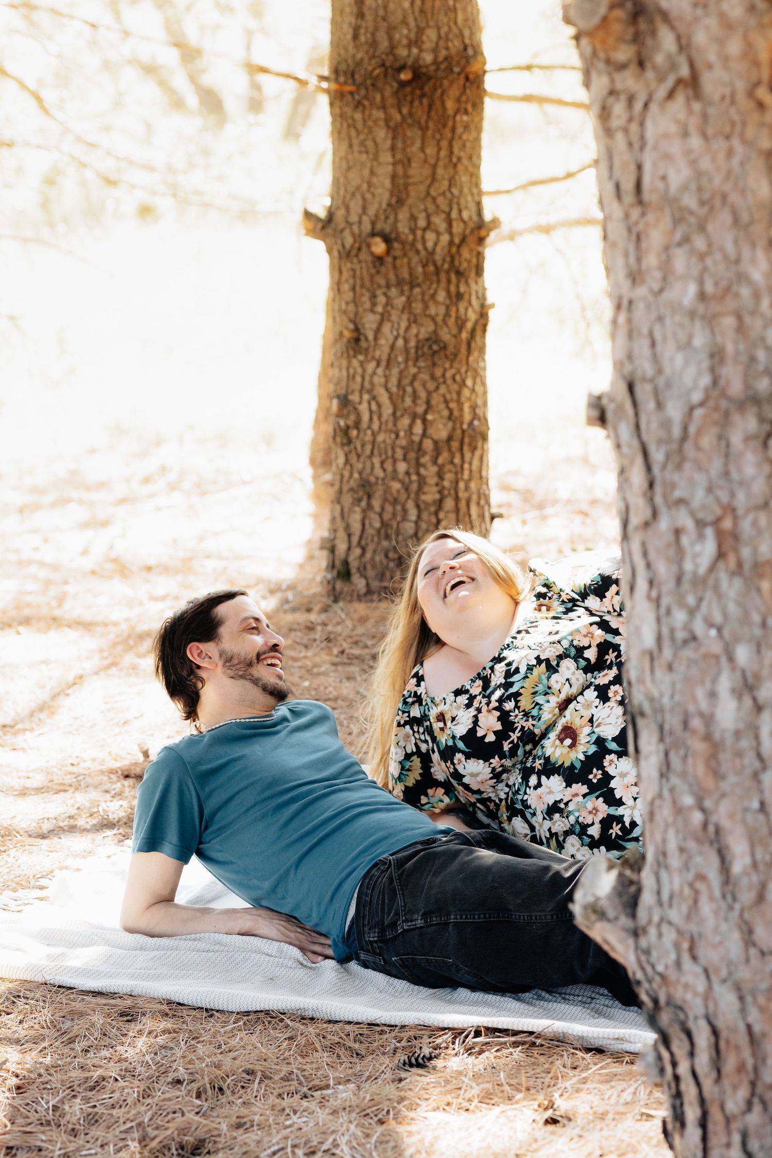 Two people lying down relaxing between pine trees on a sunny afternoon.