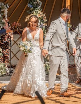 Wedding couple performs fun dance moves on a wooden deck with scattered flower petals during their celebration.
