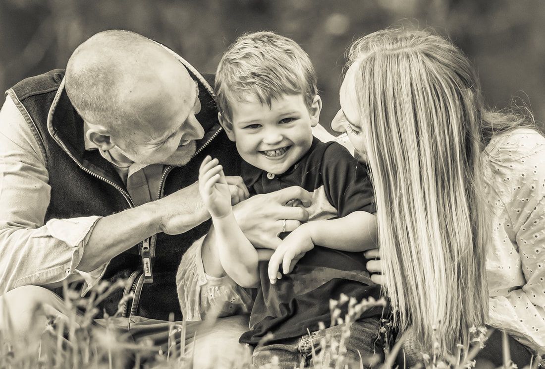 A black and white collage of family moments showing tender interactions between adults and children outdoors.