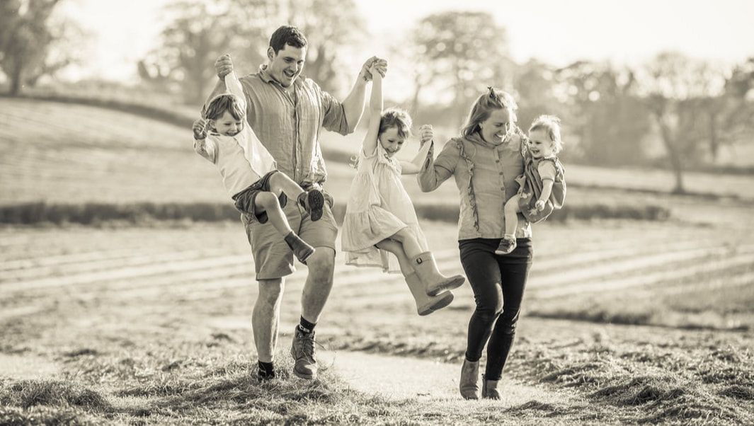 A couple runs playfully through a field together in black and white photography.