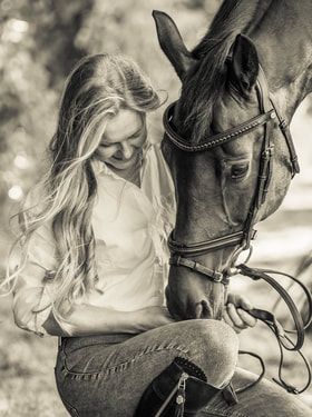 Two people riding horses side by side in black and white photograph with dramatic lighting and bokeh effect.