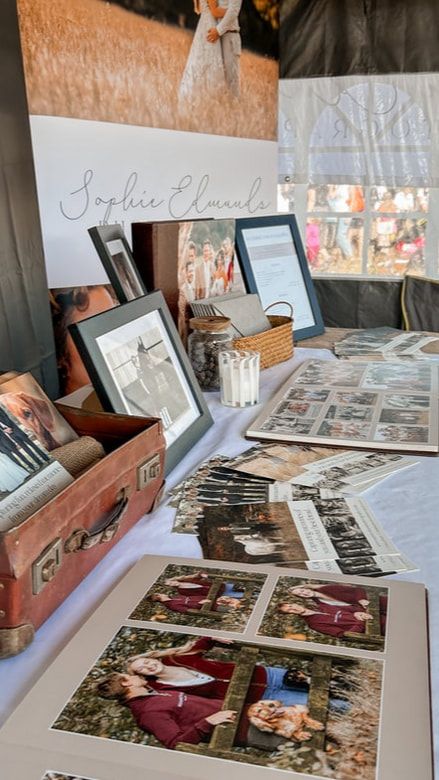 A collection of vintage photographs and memorabilia displayed on a table with frames and an old suitcase.