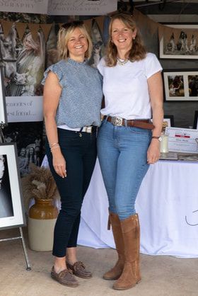 A group of people wearing jeans and boots stand together at an indoor event with white tablecloths visible.