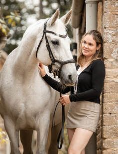A series of images showing a beautiful white horse being photographed in front of a rustic brick wall setting.