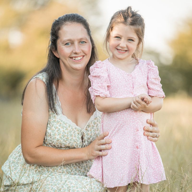 A heartwarming outdoor family photoshoot in a field during golden hour with soft natural lighting.