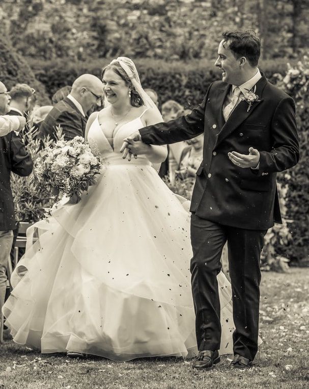 A black and white wedding photo series showing the couple and guests celebrating with confetti in an outdoor setting.