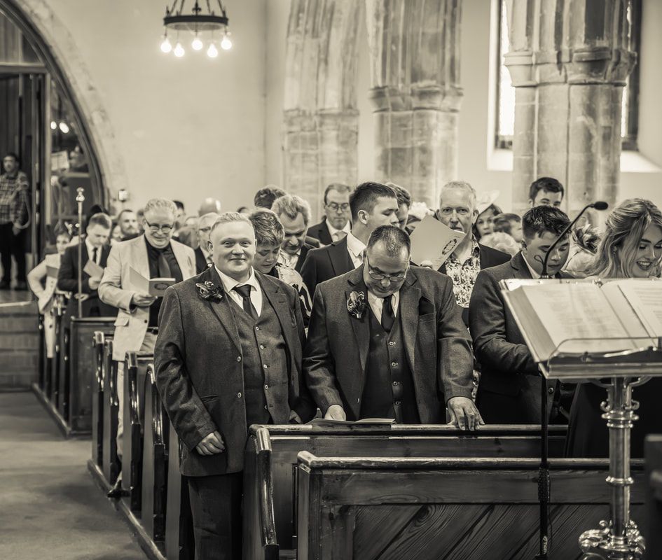 A black and white panoramic photograph showing a group of formally dressed people seated in church pews during a service.