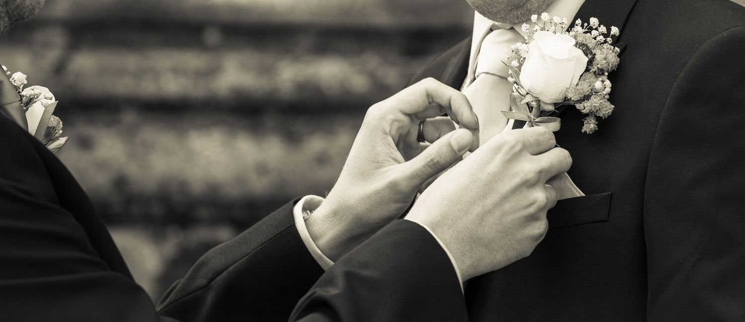 Close-up black and white detail of hands holding a wedding bouquet.