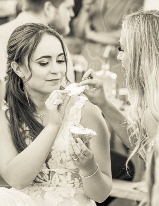 Black and white photo of two people enjoying dessert at a formal event, with one person taking a bite of cake.