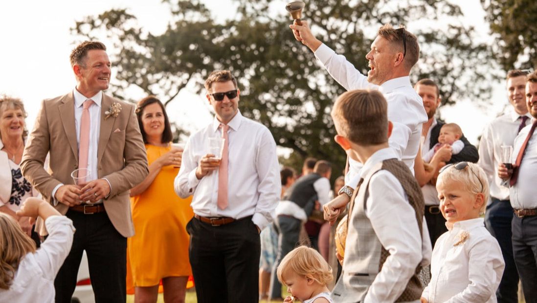 A group of wedding guests enjoying drinks and conversation outdoors during a sunset reception celebration.