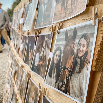 Row of portrait photographs clipped to a rustic string display against a wooden background.
