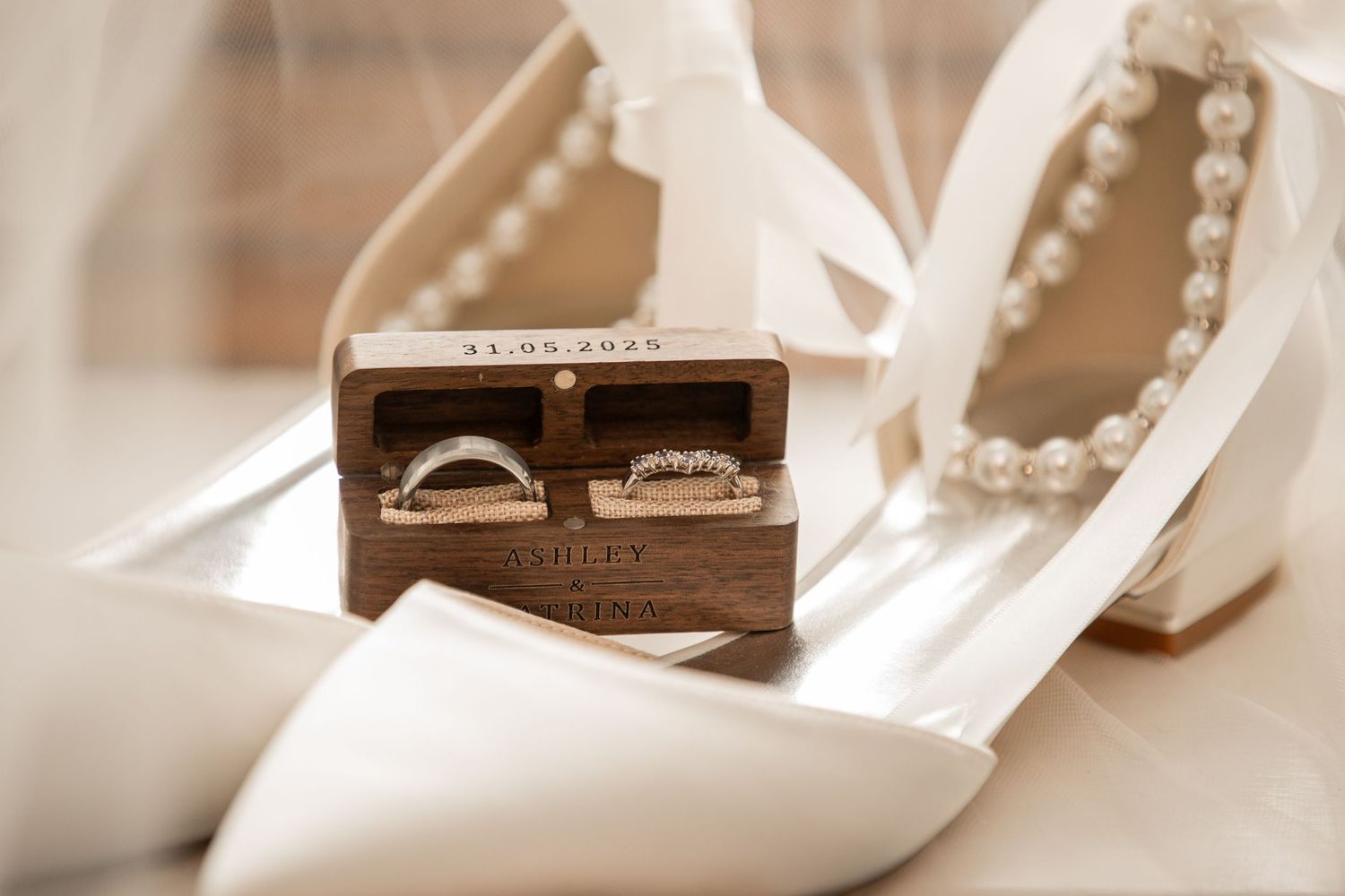 Elegant wedding rings rest on a white surface with soft bokeh lighting in the background.