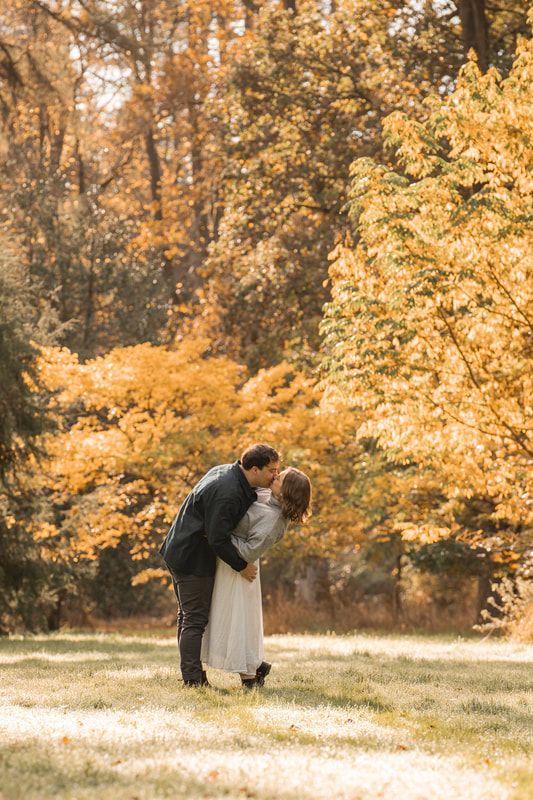 A romantic autumn scene with a couple embracing under golden foliage in a sunlit park setting.